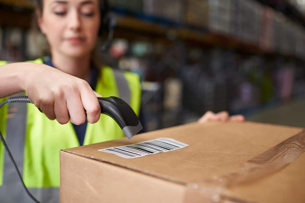 Woman using barcode rf scanner on a box in a warehouse