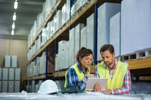 Two warehouse employees working on an inventory management software.